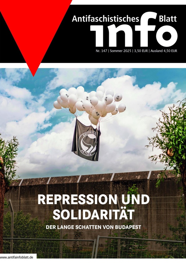Ein Solidaritätstransparent fliegt an Luftballons über eine Knastmauer.